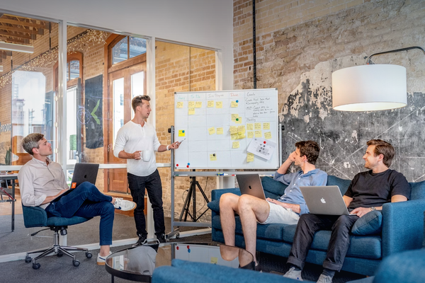 Team discussing project details near laptop and whiteboard